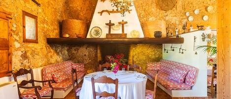 A rustic dining area with a round table, wooden chairs, and benches.