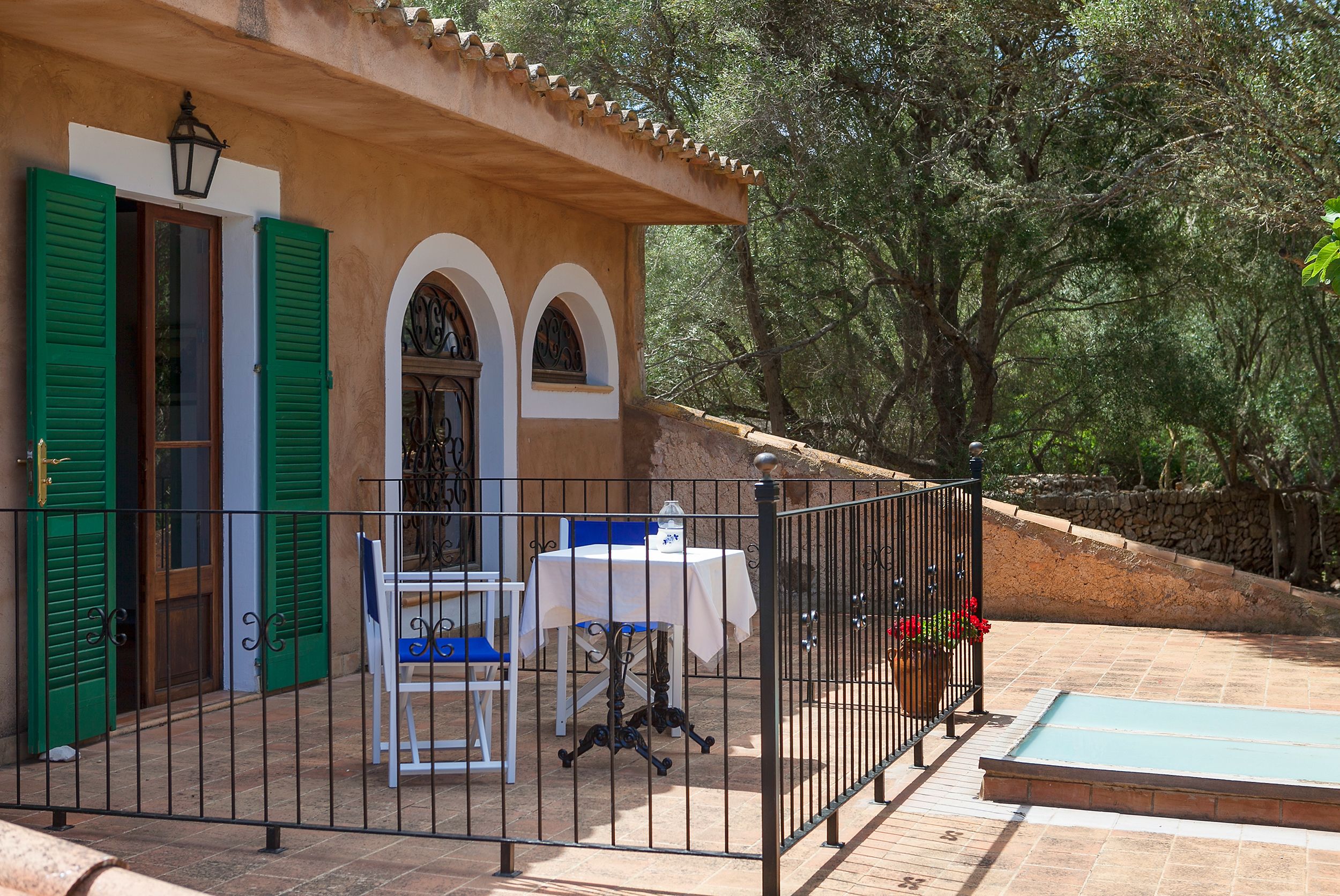 A patio with a table and chairs, a small pool, and a stone wall.