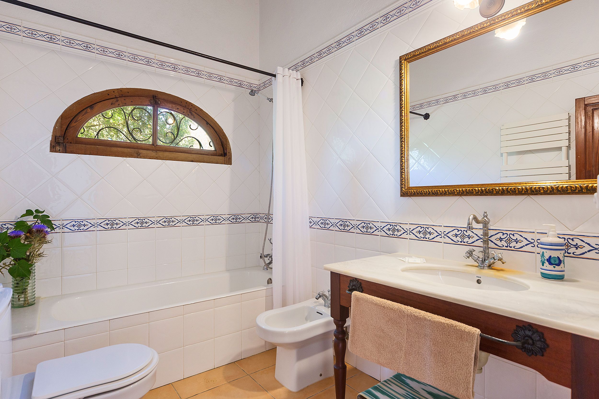 A bathroom with a bathtub, a bidet, a sink, and a mirror.