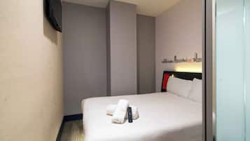 Habitación de hotel con cama, control remoto y un cuadro de arte con un paisaje urbano.