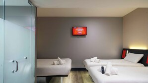 A hotel room with two beds, a TV on the wall, and a glass door. - easyHotel Sheffield (Sheffield)