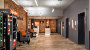 A modern hotel lobby with a coffee machine, seating area, reception desk, and a brick wall. - easyHotel Sheffield (Sheffield)
