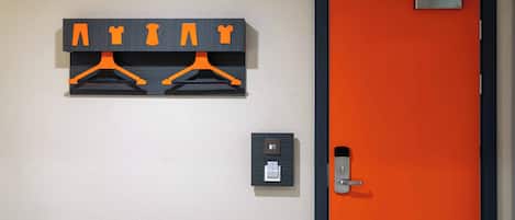 Una habitación con una puerta, un perchero en la pared con ganchos y un enchufe.