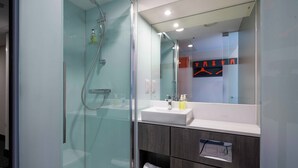 A modern bathroom with a glass-enclosed shower, a white sink, and dark wood cabinets. - easyHotel Sheffield (Sheffield)