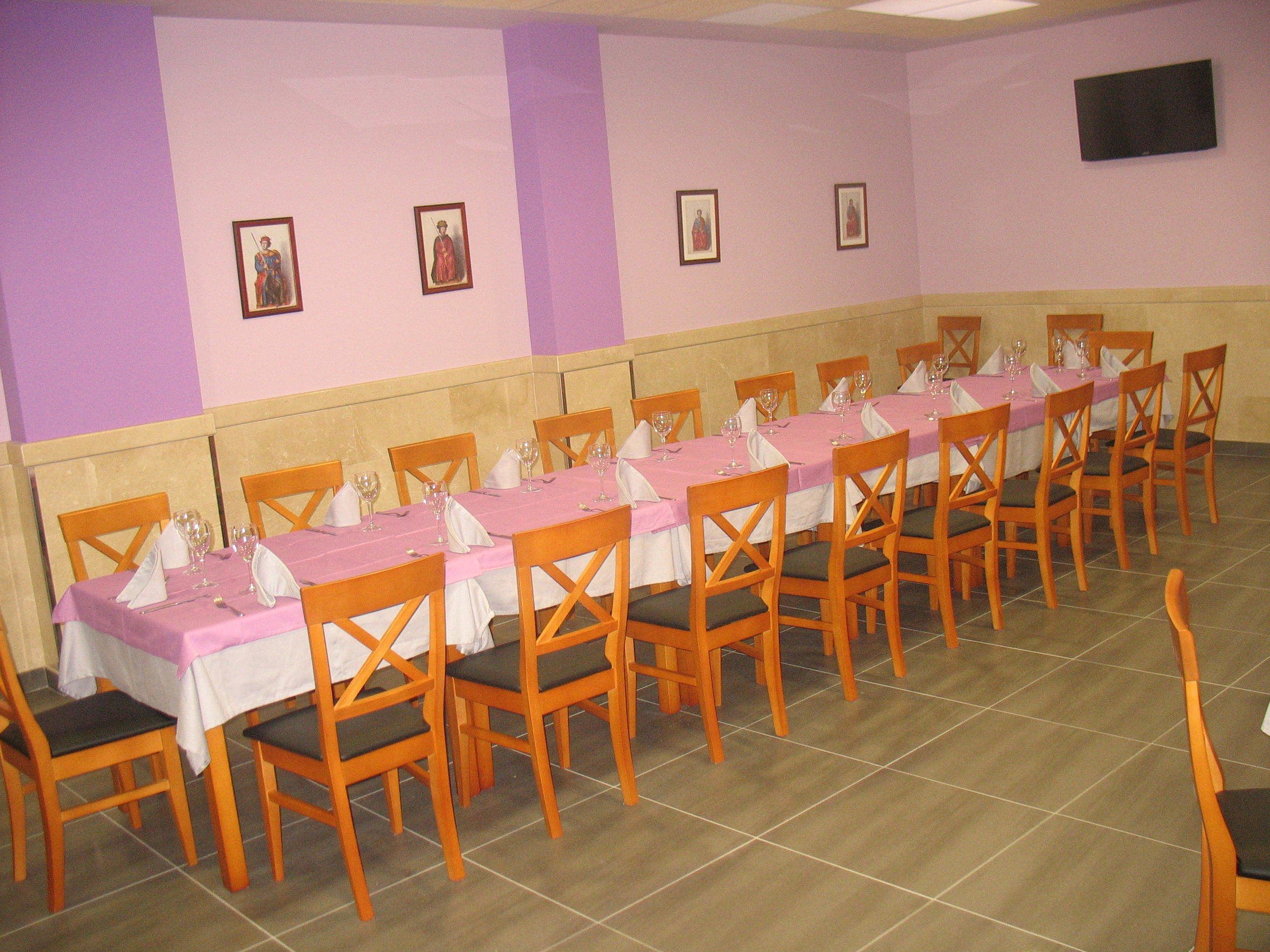 Uma sala de jantar com várias mesas postas para refeição, cadeiras de madeira e piso ladrilhado.