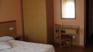 A bedroom with a bed, a wooden desk, and a chair.