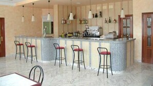 A bar area with a marble countertop, bar stools, hanging pendant lights, and a minibar. - Hotel Reyes de León (Santa Maria del Paramo)