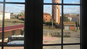 A view through a window with a clear sky and a water tower in the distance. - Hotel Reyes de León (Santa Maria del Paramo)