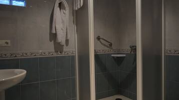 Un baño con ducha, lavamanos y toallero.