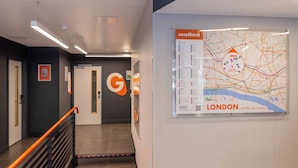 Un pasillo con una escalera, un letrero con el logotipo G y un mapa de Londres en la pared.