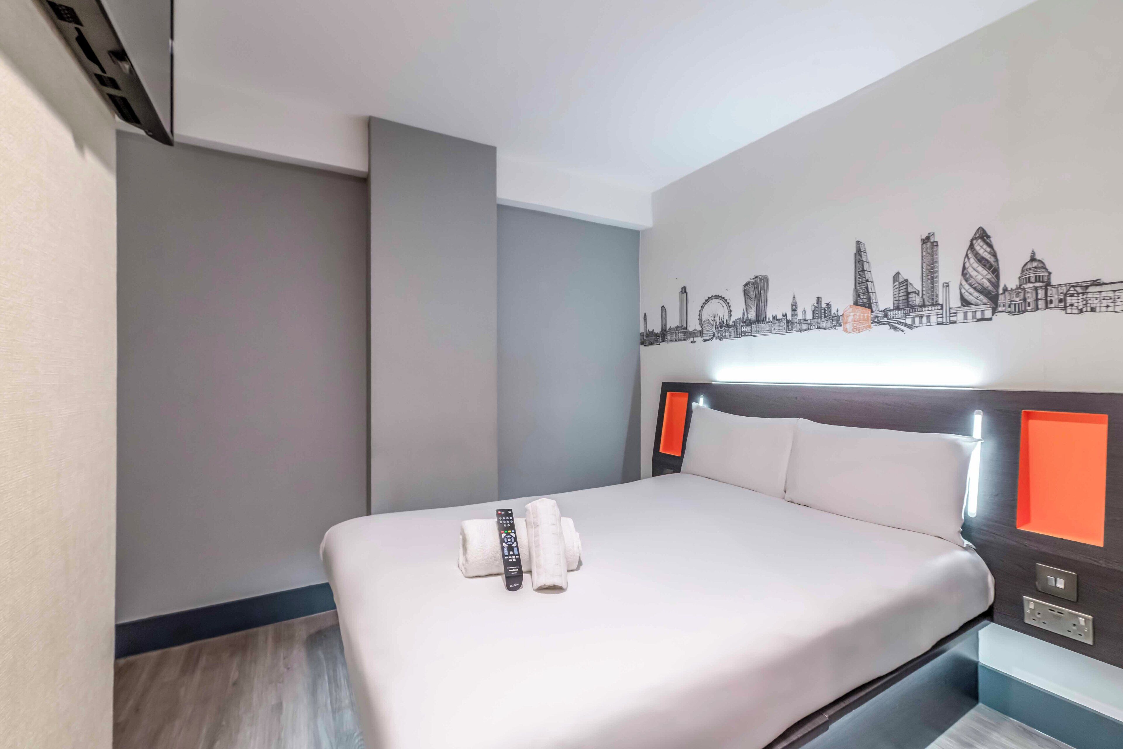 Una habitación de hotel con una cama bien hecha, un control remoto y una toalla.