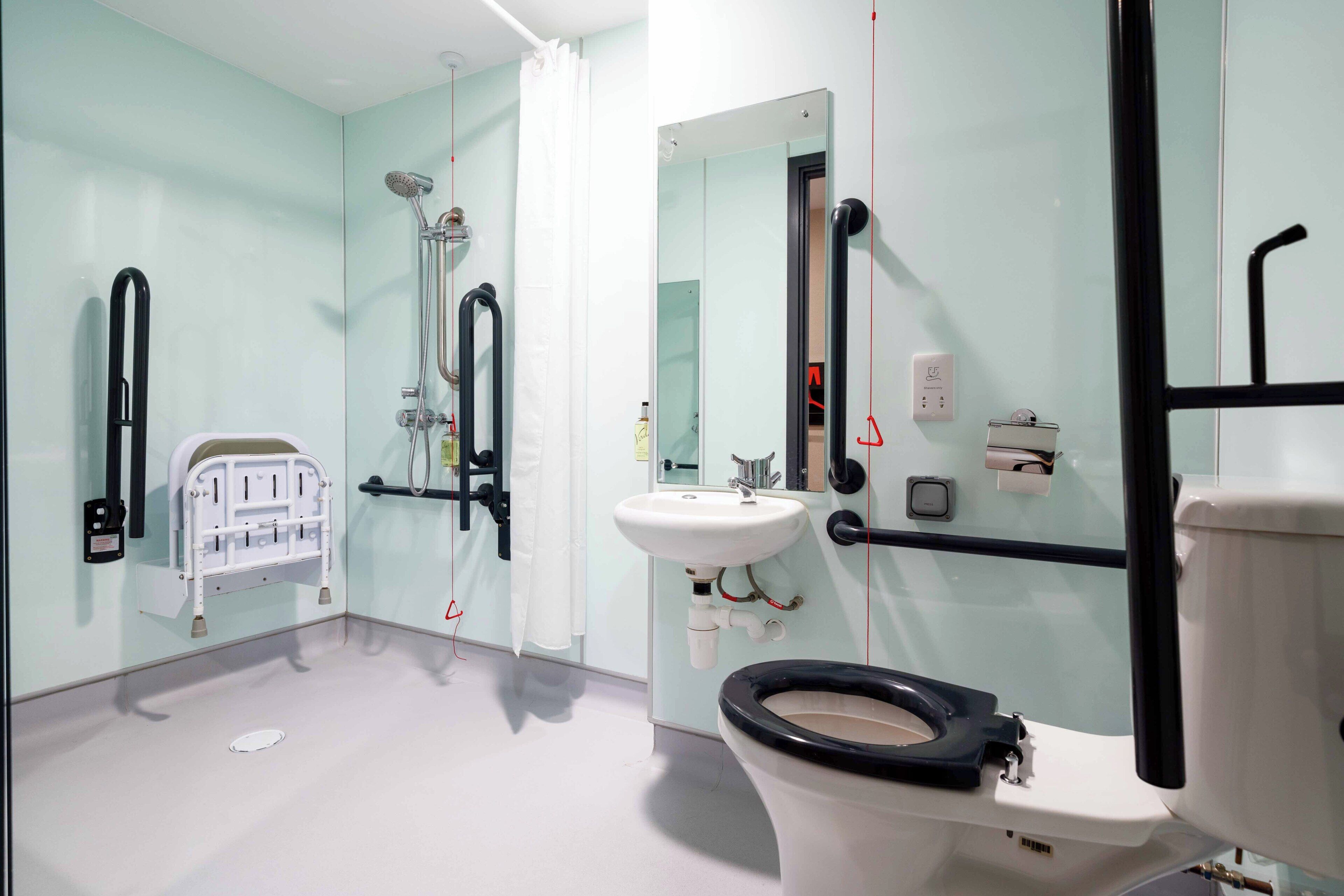 Une salle de bain avec des toilettes blanches, un lavabo, une douche et un miroir.