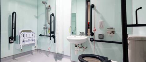 A bathroom with a white toilet, a sink, a shower, and a mirror.