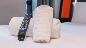 Un control remoto, una toalla enrollada y una almohada sobre la cama.