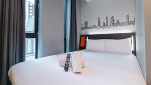 Habitación de hotel con cama, control remoto y toalla.