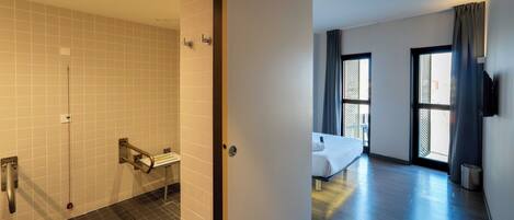 Ein Hotelzimmer mit Dusche, einem Bett, einem Fernseher und einem Fenster mit Vorhängen.