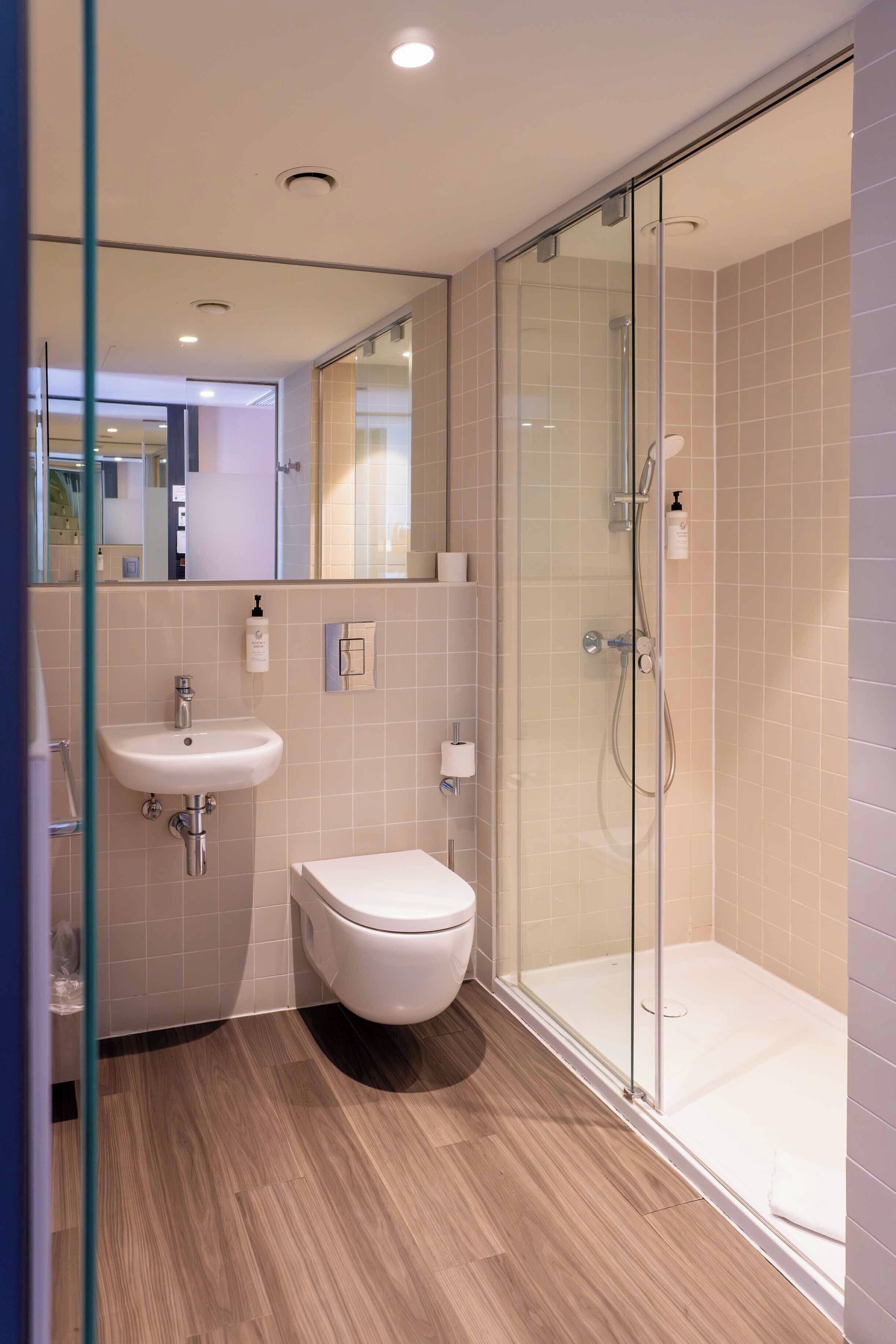 A modern bathroom with a glass-enclosed shower, a white sink, and a toilet.