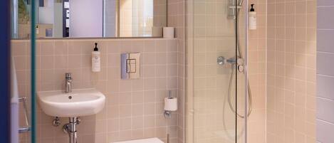 A modern bathroom with a glass-enclosed shower, a white sink, and a toilet.