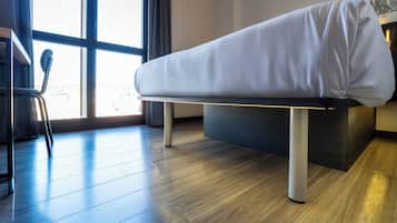 A modern room with a bed, a chair, and a large window.