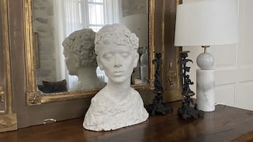 A wooden dresser with a white bust sculpture, a mirror, and a lamp.