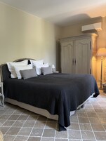 A bedroom with a bed, a wardrobe, a nightstand, and a lamp.