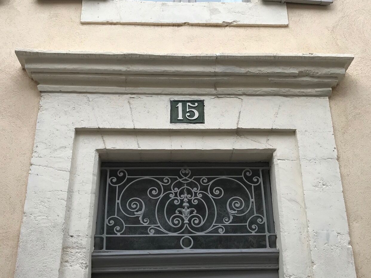 A building facade with a number '15' above a window with ornate metal bars.