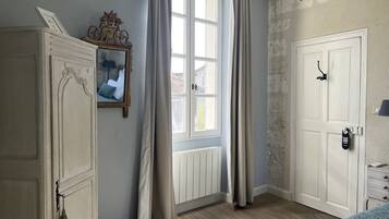 Et værelse med et stort vindue, en radiator, et skab og en dør med et skilt.
