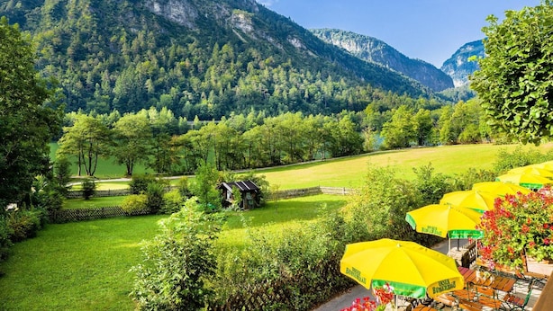 Un paisaje montañoso con un campo verde, un edificio pequeño y sombrillas amarillas.