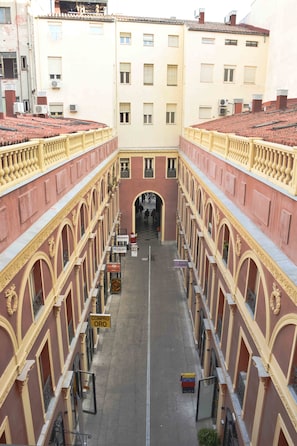 A courtyard with a central archway, surrounded by buildings with balconies and railings. - Hostal Guestped (Madrid)