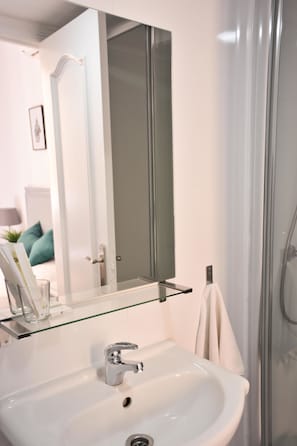A modern bathroom with a white sink, a glass shelf, and a large mirror. - Hostal Guestped (Madrid)