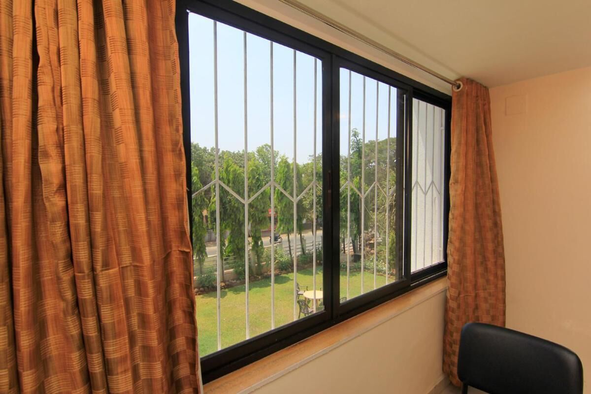 A room with a window, curtains, and a chair.