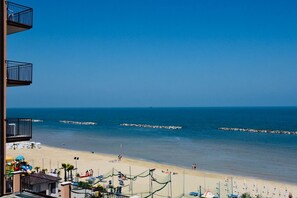 A beach view with a clear sky, a sandy beach, and a rocky breakwater. - Hotel Astoria Pesaro (Pesaro)