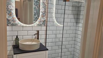 Habitación Deluxe doble | Baño | Cabezal de ducha tipo lluvia y artículos de higiene personal gratuitos