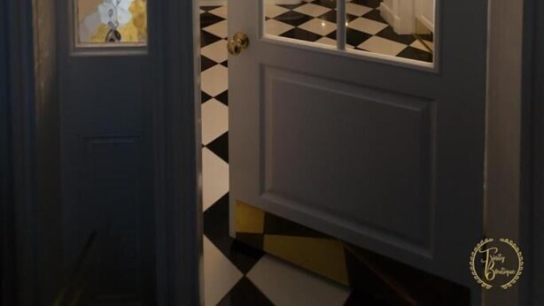 Un couloir avec un sol à carreaux noirs et blancs, une porte blanche avec des panneaux de verre, et un escalier en arrière-plan.