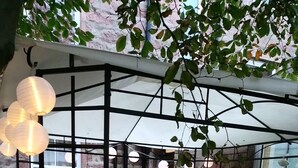 Un espace extérieur aménagé avec une pergola, des tables, des chaises et des guirlandes lumineuses.