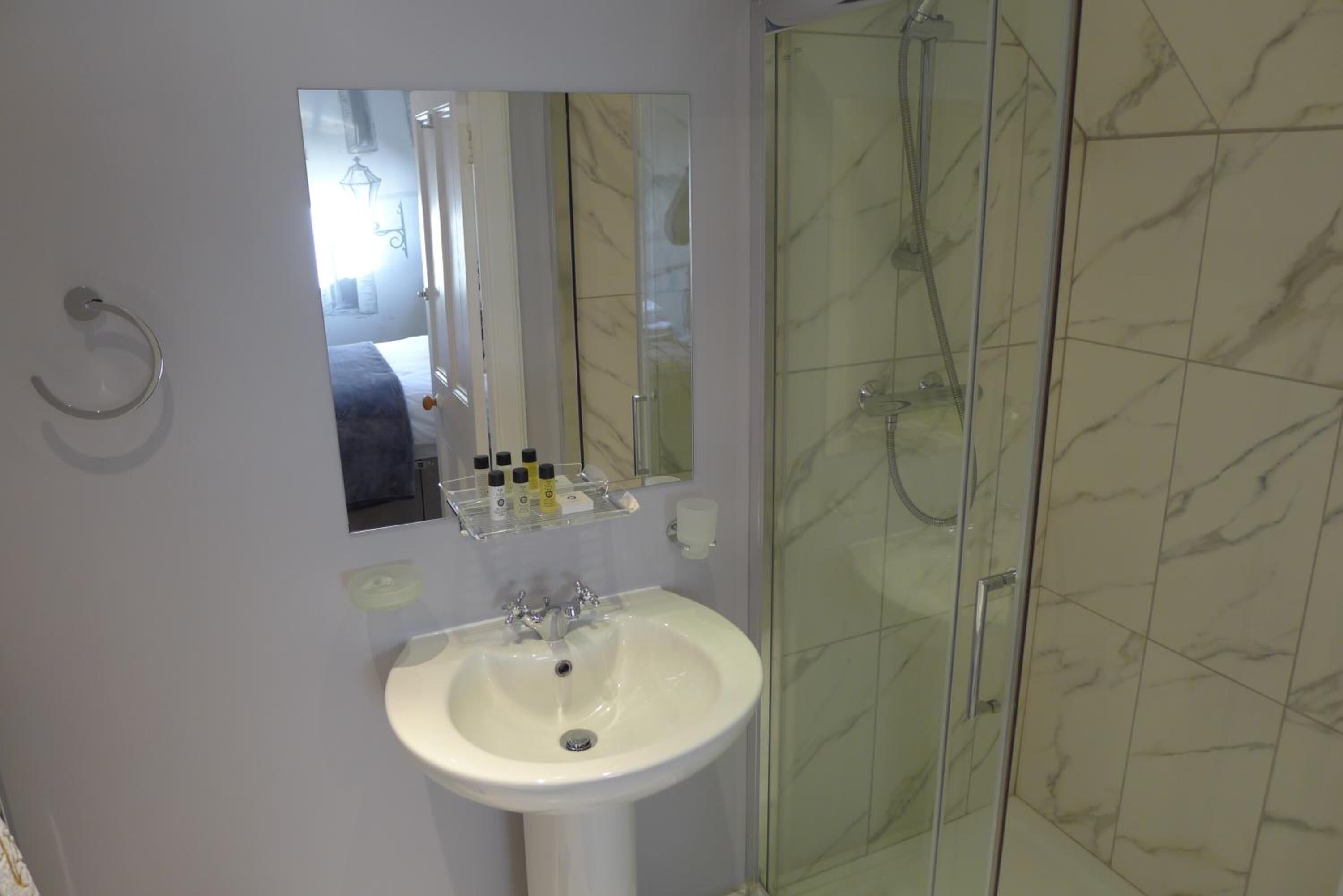 A bathroom with a white sink, a mirror, and a glass-enclosed shower.