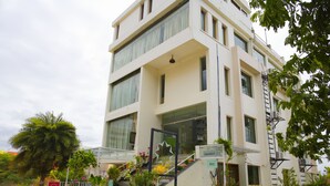 Un edificio de varios pisos con diseño moderno, que cuenta con una escalera con plantas en macetas que conduce a la entrada.