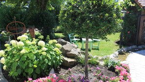A garden with a 'Willkommen' sign, a small tree, and a variety of flowers. - Landhotel Kastanienhof (Georgenberg)