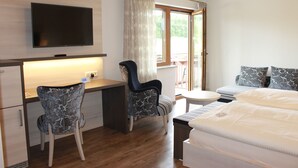 A hotel room with a bed, two chairs, a desk, a TV, and a window with curtains. - Landhotel Kastanienhof (Georgenberg)