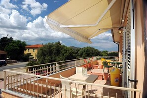 A balcony with a white railing, outdoor seating, and a yellow umbrella. - B&B Le Dune (San Teodoro)