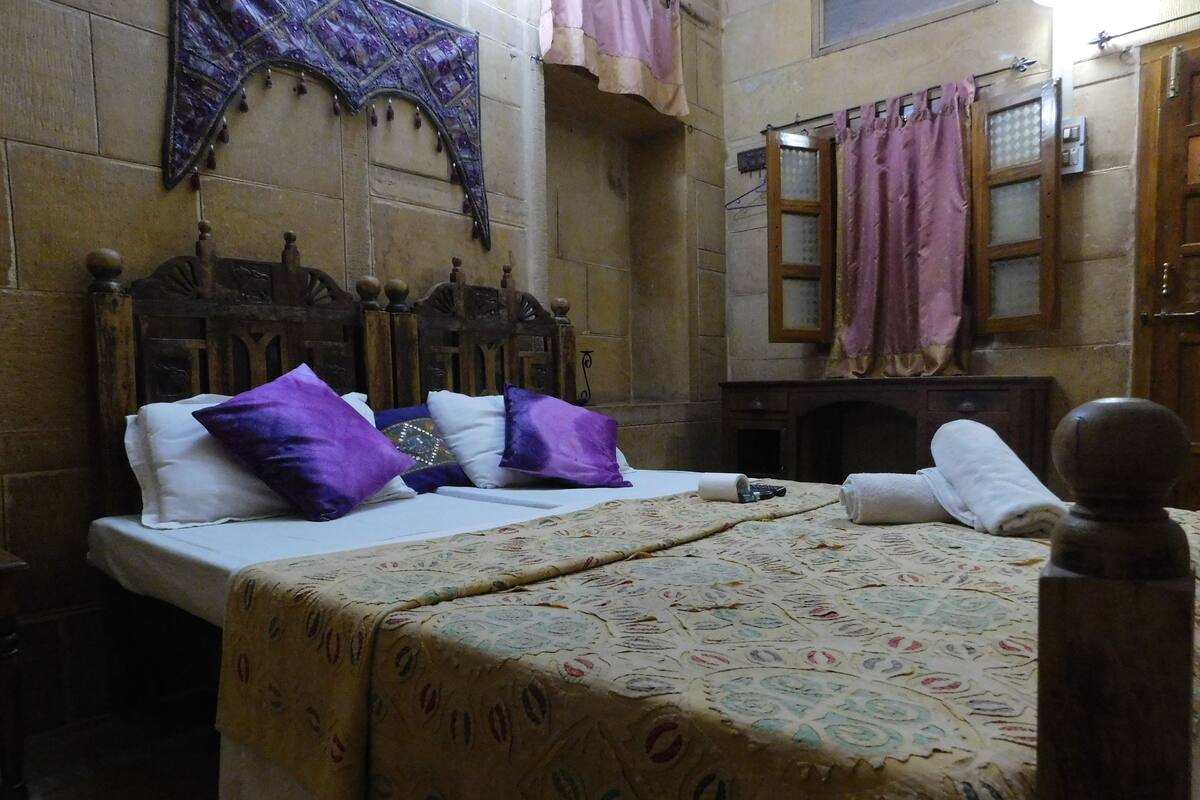 A traditional room with a bed, wooden headboard, and a patterned bedspread.