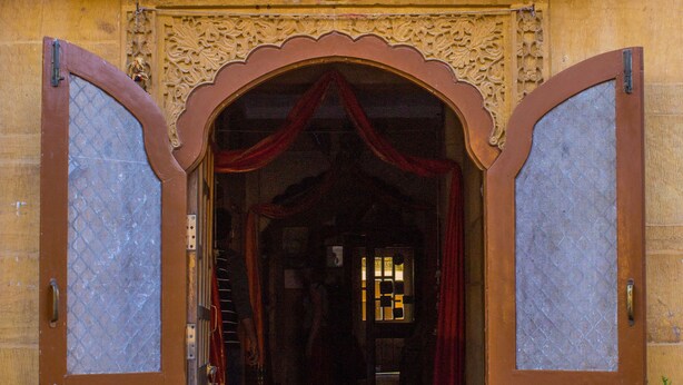 Una entrada ornamentada con un arco decorativo y una puerta de metal.
