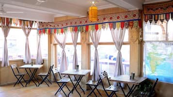 A room with a traditional design, featuring a wooden table and chairs, a map on the wall, and a decorative hanging.