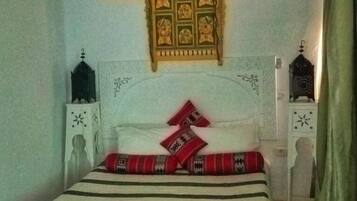 Ein Bett mit weißem Kopfteil, rot-schwarz gestreifter Bettwäsche und einem dekorativen Wandbild darüber.