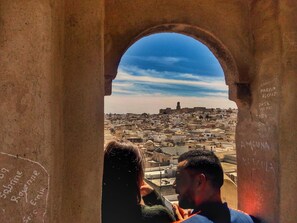 A view through an archway of a cityscape with buildings and a distant tower. - Dar Baaziz (Sousse)