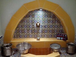 A bathroom with a tiled arch and a sink with three metal buckets.