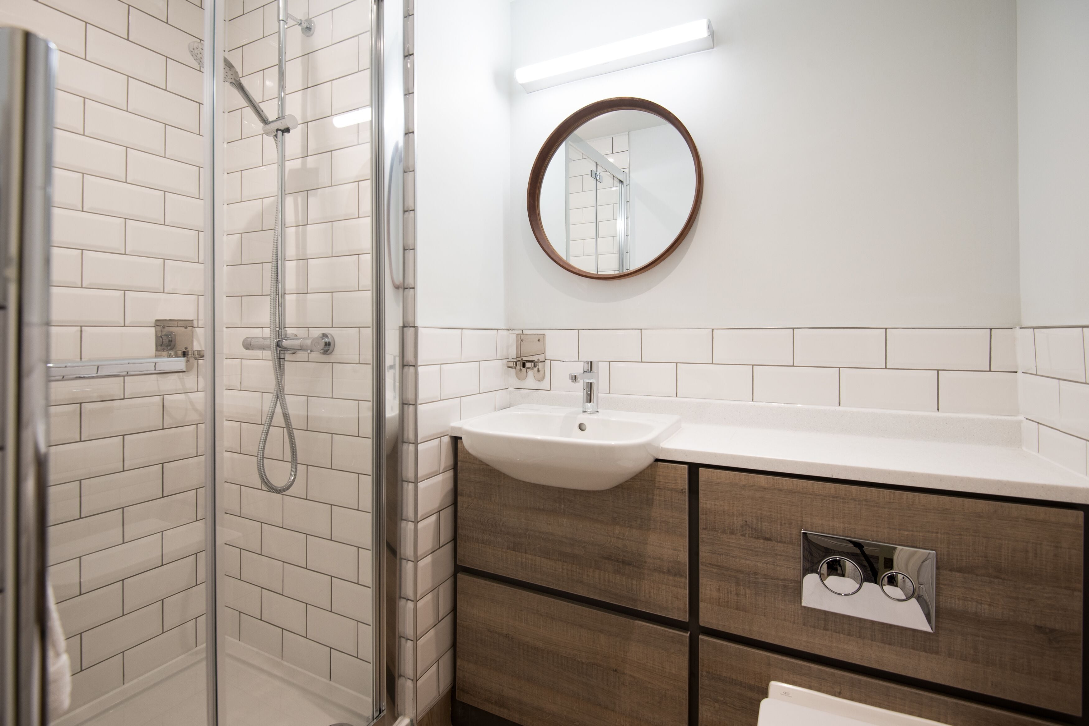 A modern bathroom with a glass-enclosed shower, a white sink, and wooden cabinetry.