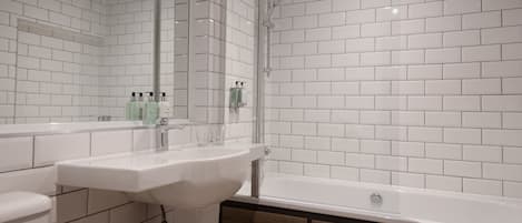 A modern bathroom with white tiled walls, a white sink, and a bathtub.