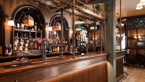 A bar area with wooden paneling, a variety of bottles, and a bar counter. - The Ullswater Inn- The Inn Collection Group (Penrith)