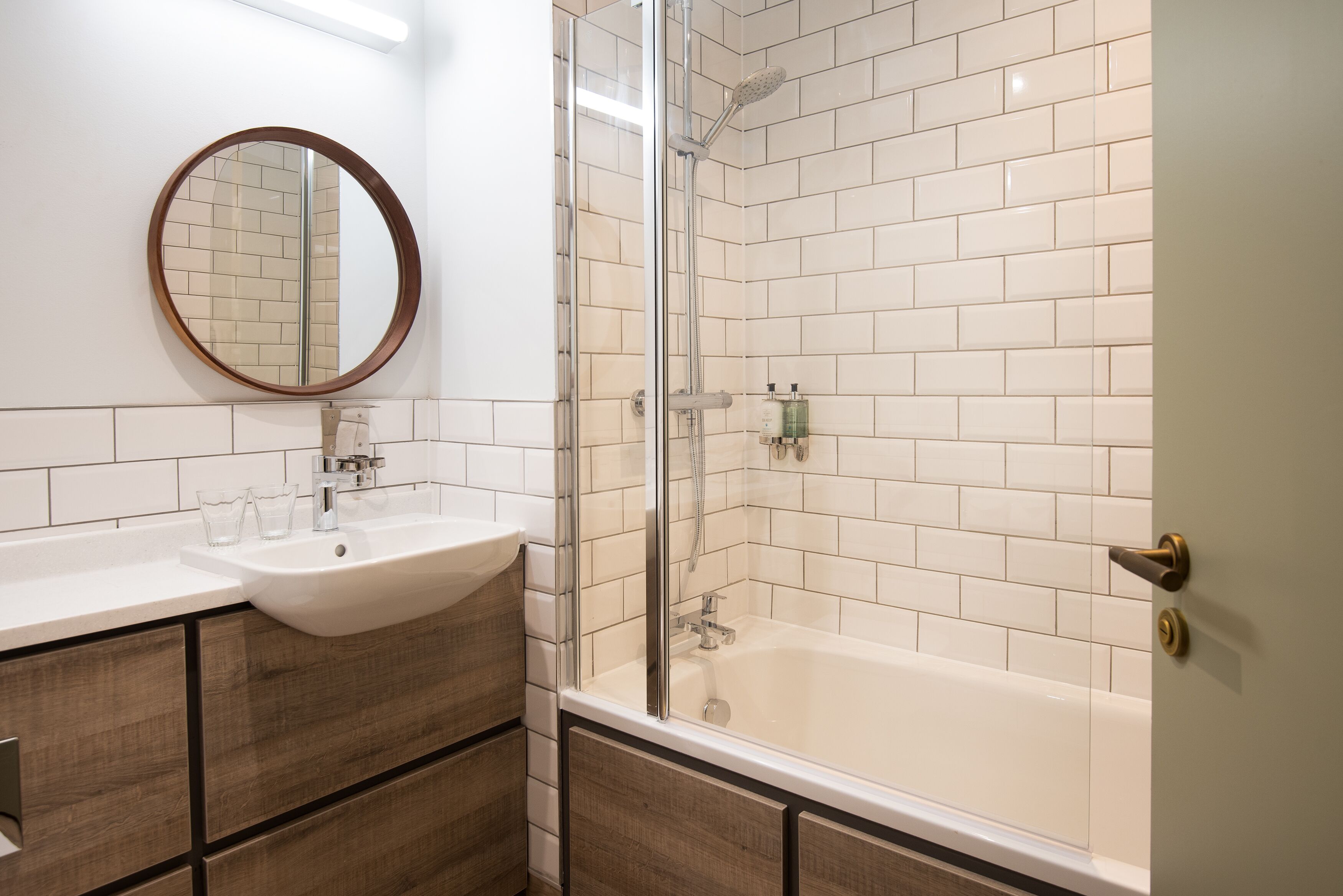 A modern bathroom with a glass-enclosed shower, a sink with a mirror, and wooden cabinetry.